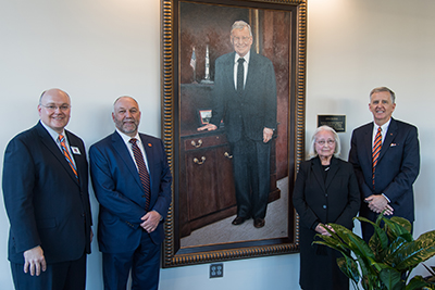 Christopher B. Roberts, dean of engineering; Steven Leath, Auburn University president; Dorothy Davidson, CEO and president of Davidson Technologies; and Michael DeMaioribus, Auburn University Board of Trustees president pro tempore with a portrait of Julian Davidson in the new Davidson Pavilion.