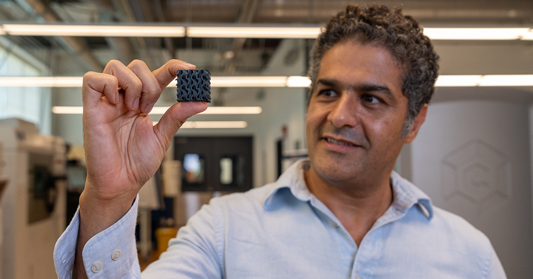 Ali Khosravi holds a small 3D-printed lattice structure in a laboratory.