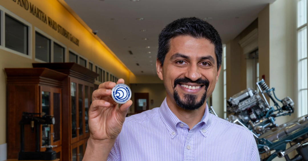 Professor holds Genesis Mission challenge coin.