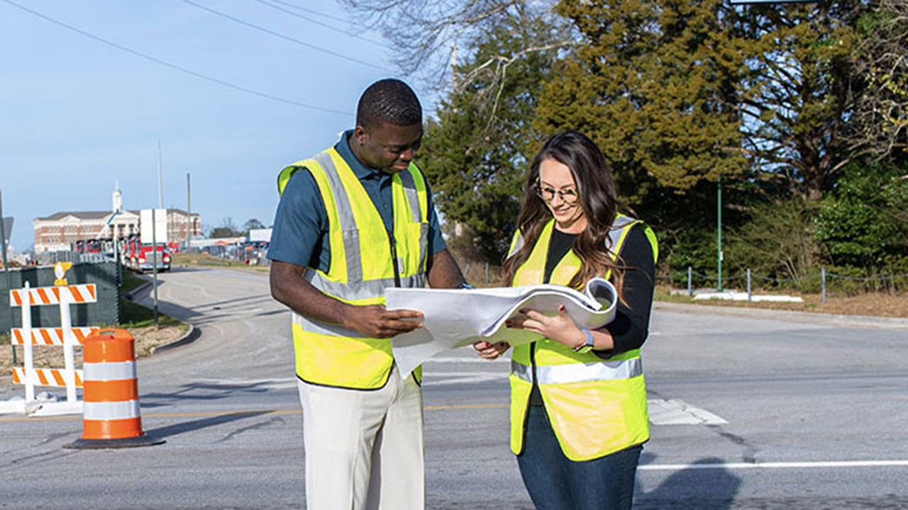 two people look at transportation plans outside 