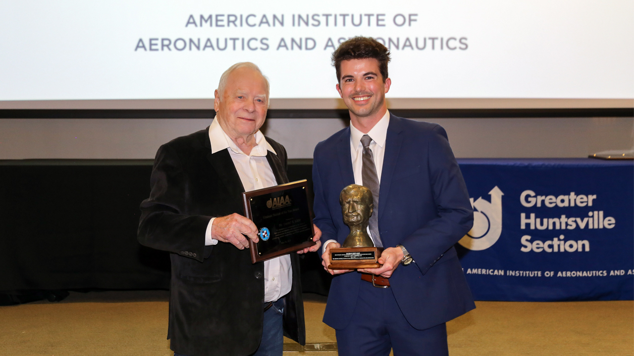 two men pose for a photo holding awards