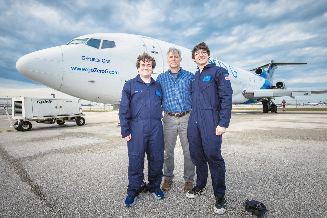 three men stand in front of a plane