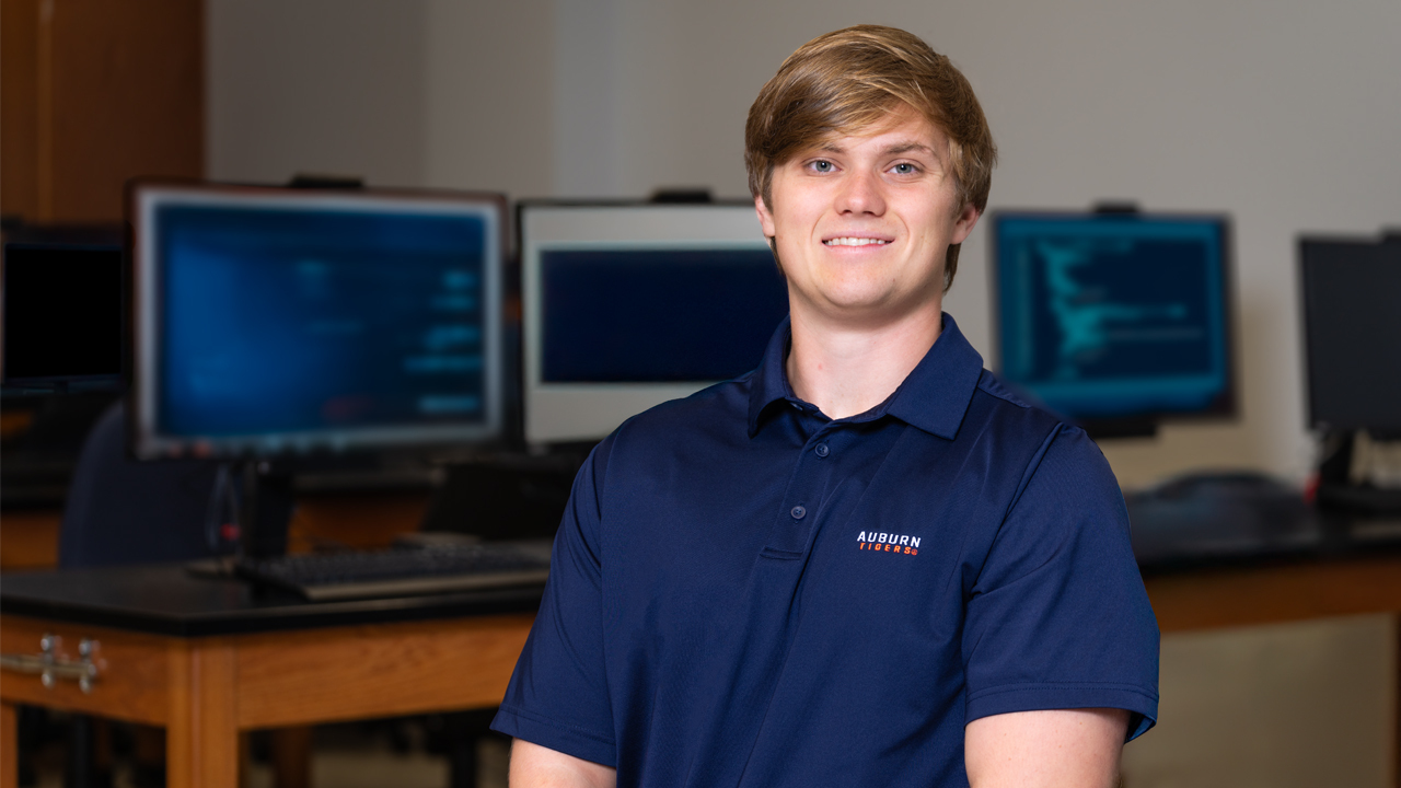 man poses for photo with computers behind him