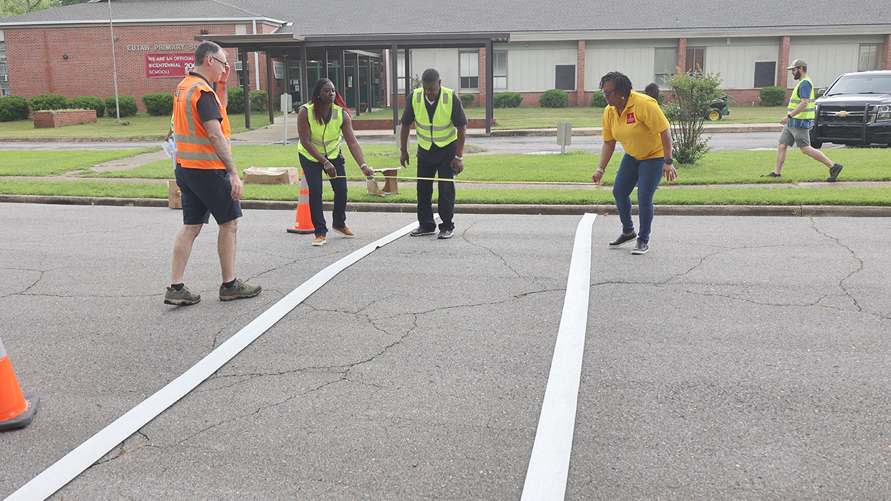 four people work to install crosswalk