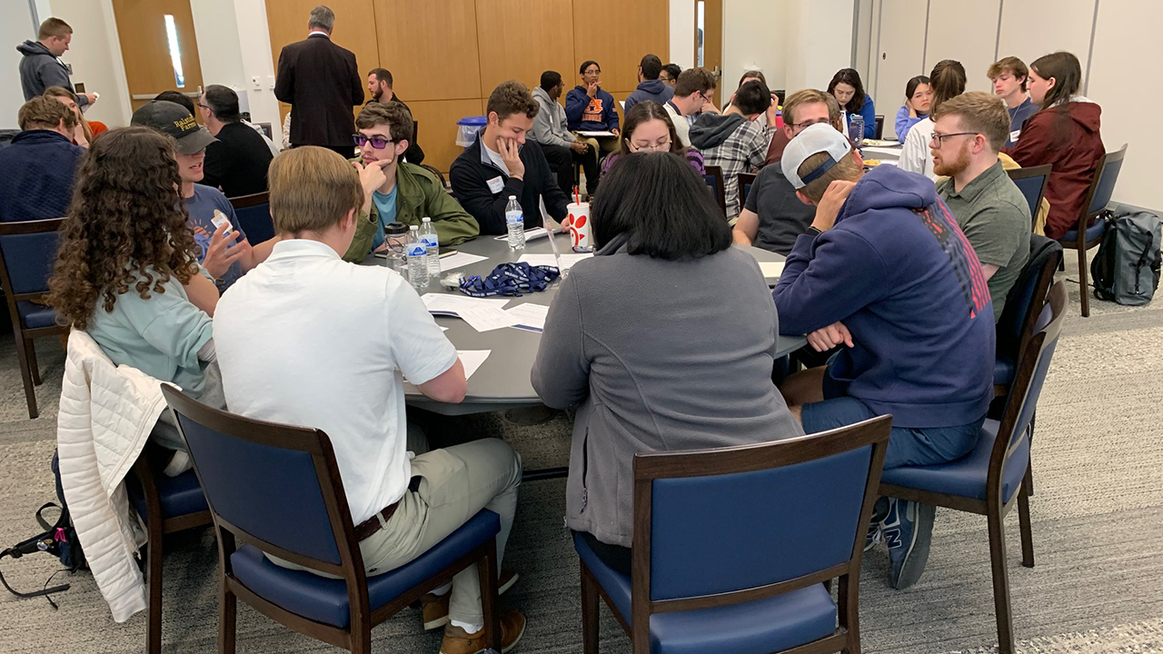 students sitting around a table in a large room