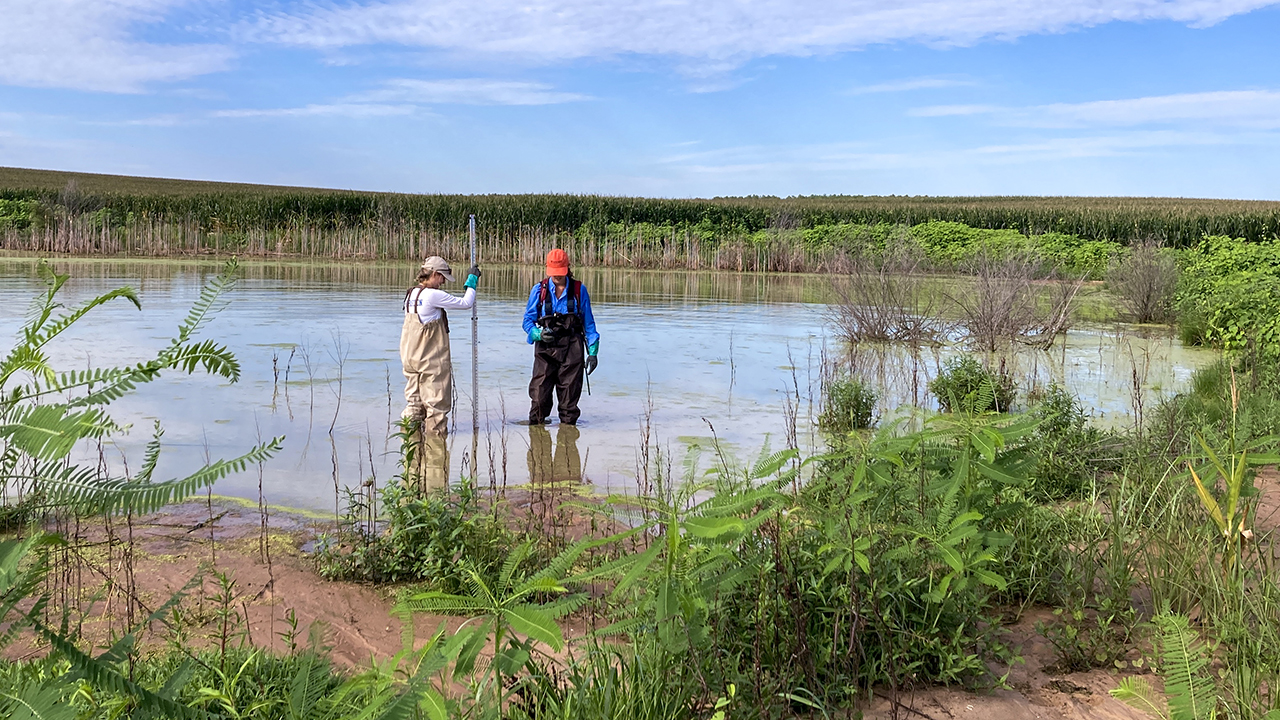 two people stand in water with a instrument to measure water levels