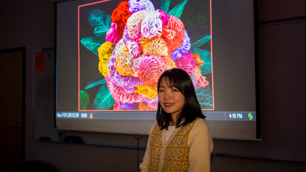 Yeonjin Baek poses in front of a display of "Flower Power," which won the grand prize in JEOL'S 2023 SEM Image Contest.