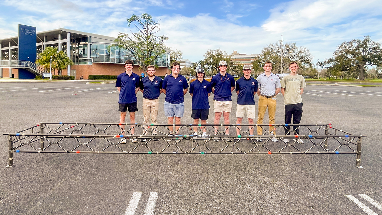 team of students stand in front of steel bridge
