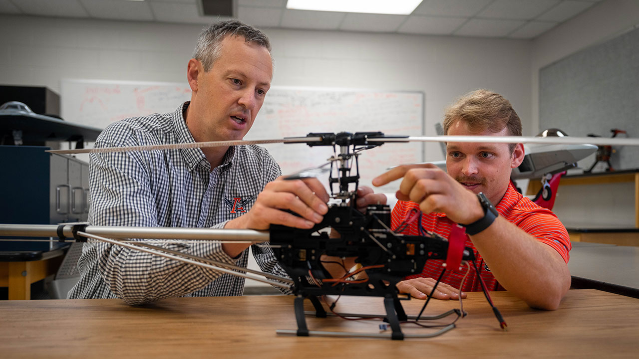 Matthew Kirchner, assistant professor in electrical and computer engineering, and graduate student Sean Bowerfind prepare a radio-controlled helicopter for testing.