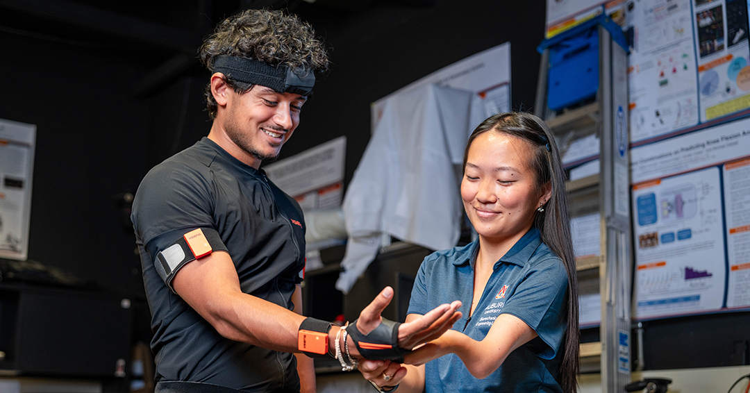 AUBE Lab graduate students Matt Ferreira-Shornack, left, and Haley Evans demonstrate wearable motion capture technology used to collect movement data for research on injury prevention.