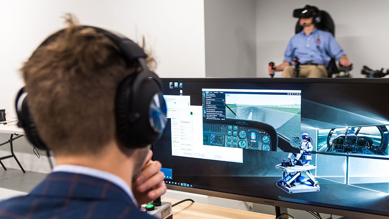 Assistant professor Umberto Saetti, seated, has the opportunity to study immersive human-machine interactions via two motion-based virtual reality rotorcraft and fixed-wing aircraft simulators.