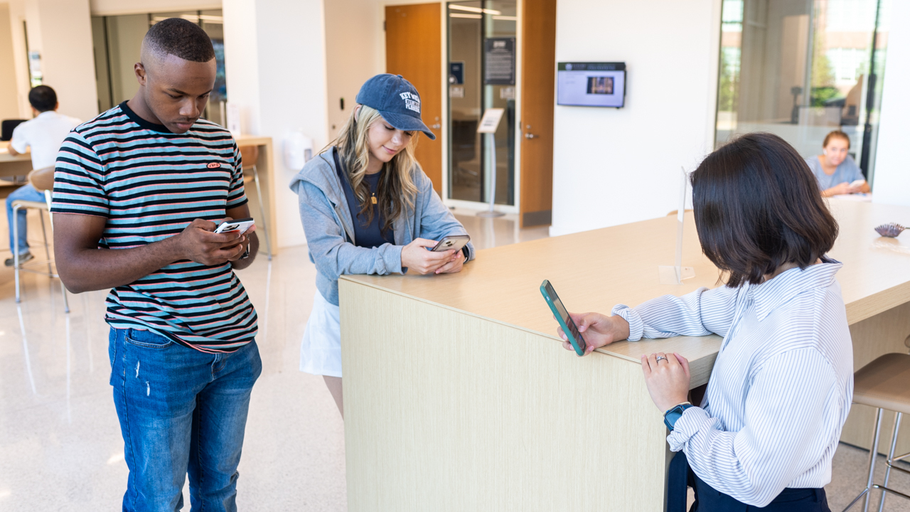 Three students look at their smartphones on Auburn University's campus. 