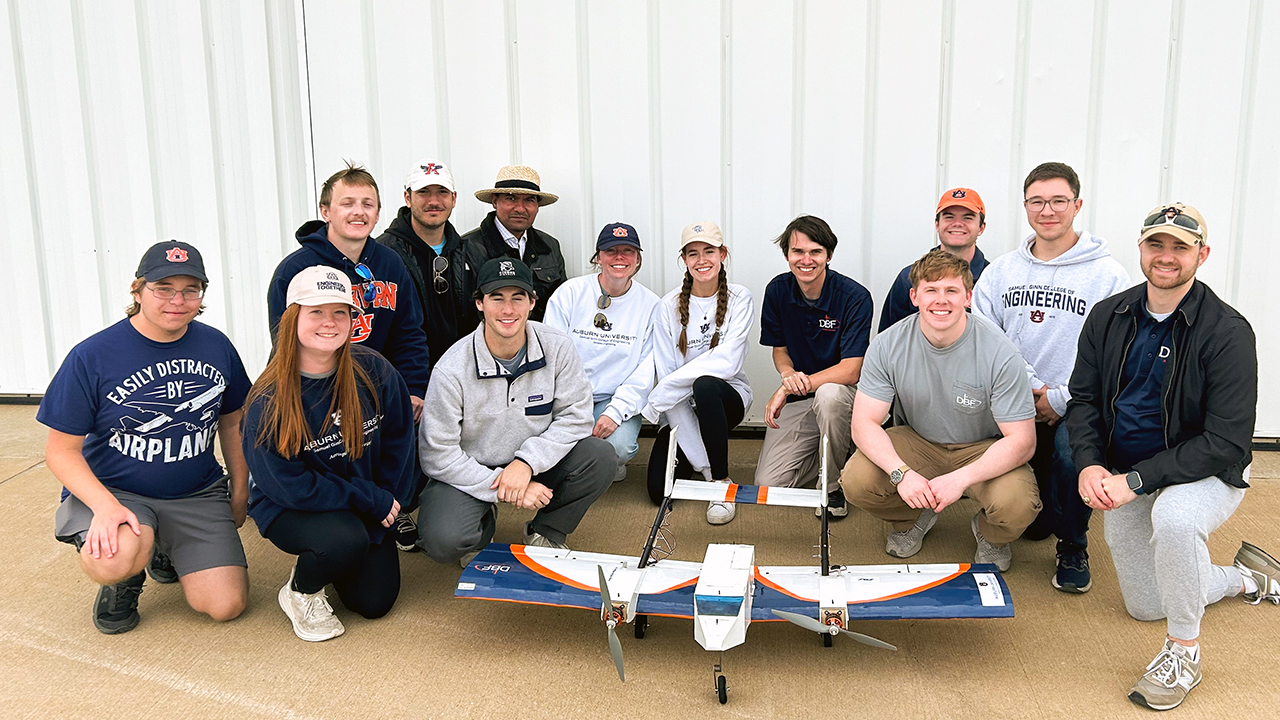 group of students pose for photo in front of plane