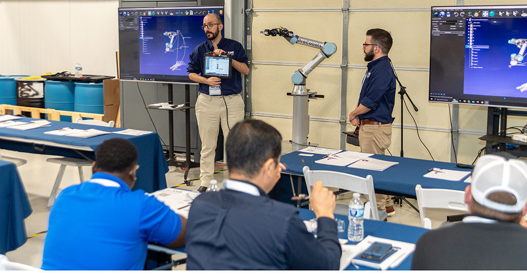 Instructor presents a digital model of a robotic system while participants watch during an ICAMS training workshop.