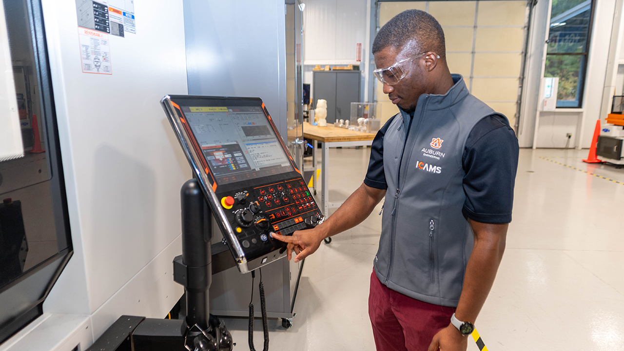 A student employee at Auburn University's Interdisciplinary Center for Advanced Manufacturing Systems (ICAMS) works a machine at the ICAMS research facility. 