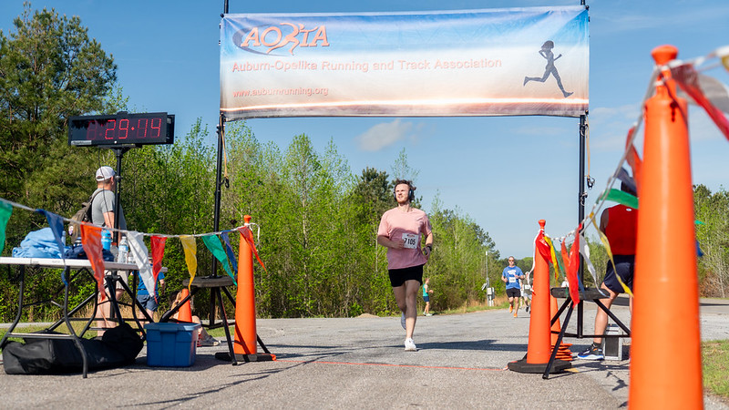 Runner crossing the finish line at the AAPT 5k at the NCAT Test Track